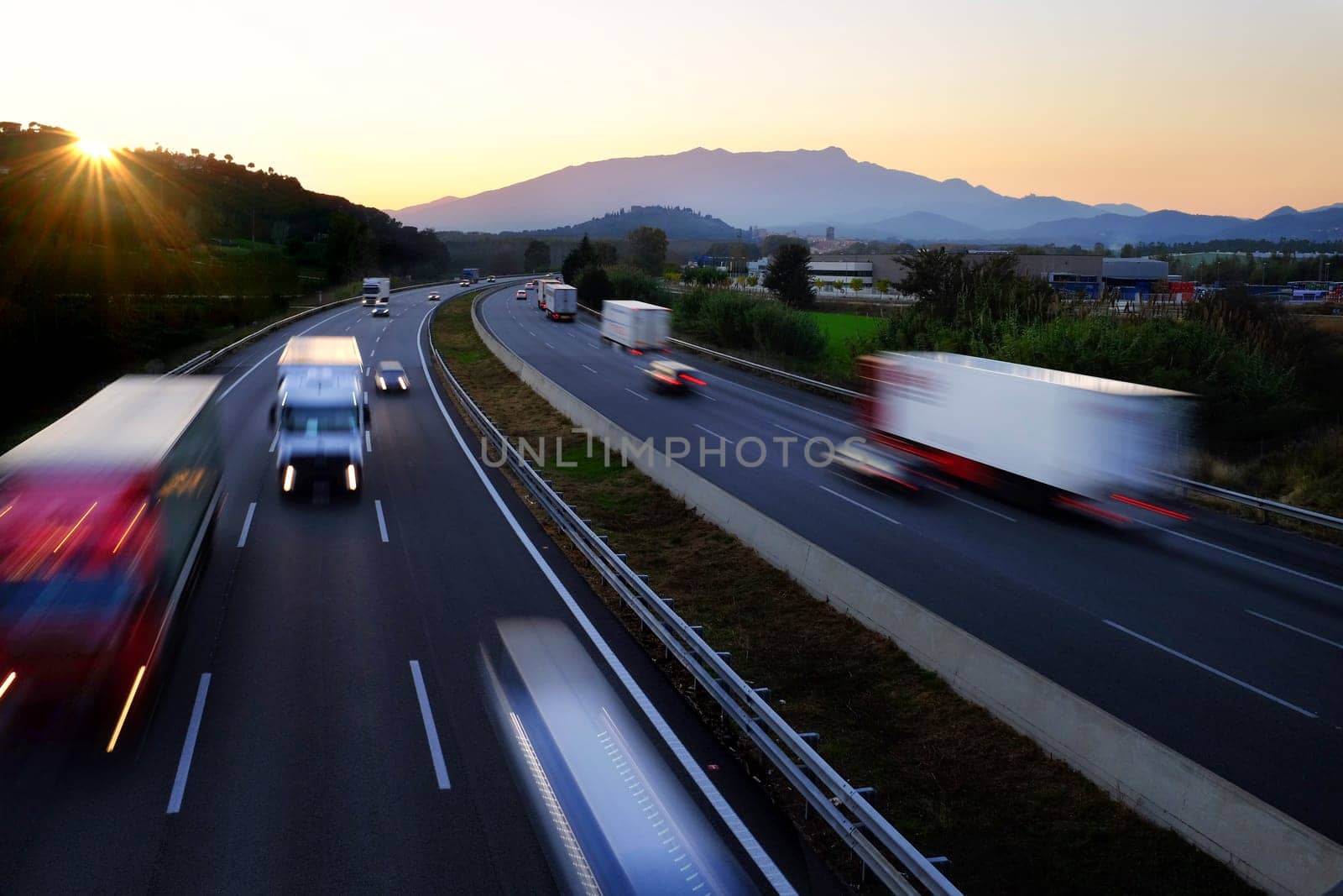 Colorful Twilight scene of frenetic highway with fast moving vehicles in blurry motion.