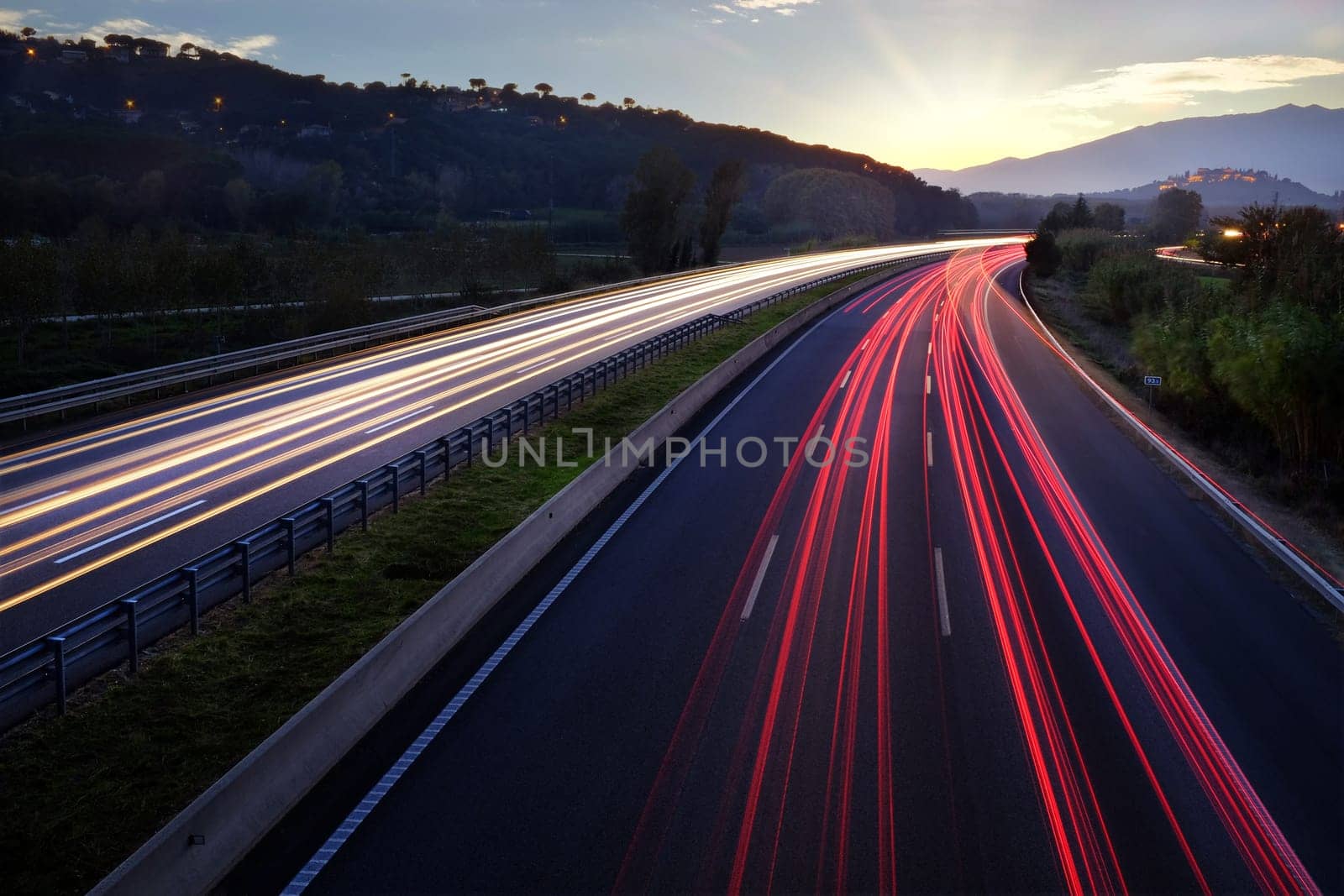 Colorful Light beams of moving vehicles on busy highway at dusk.
