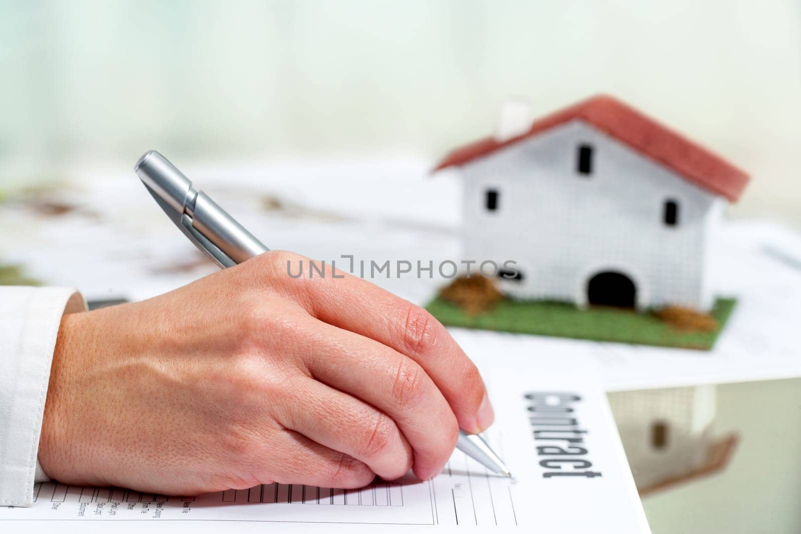 Close up of female hand filling out real estate buying and selling contract.