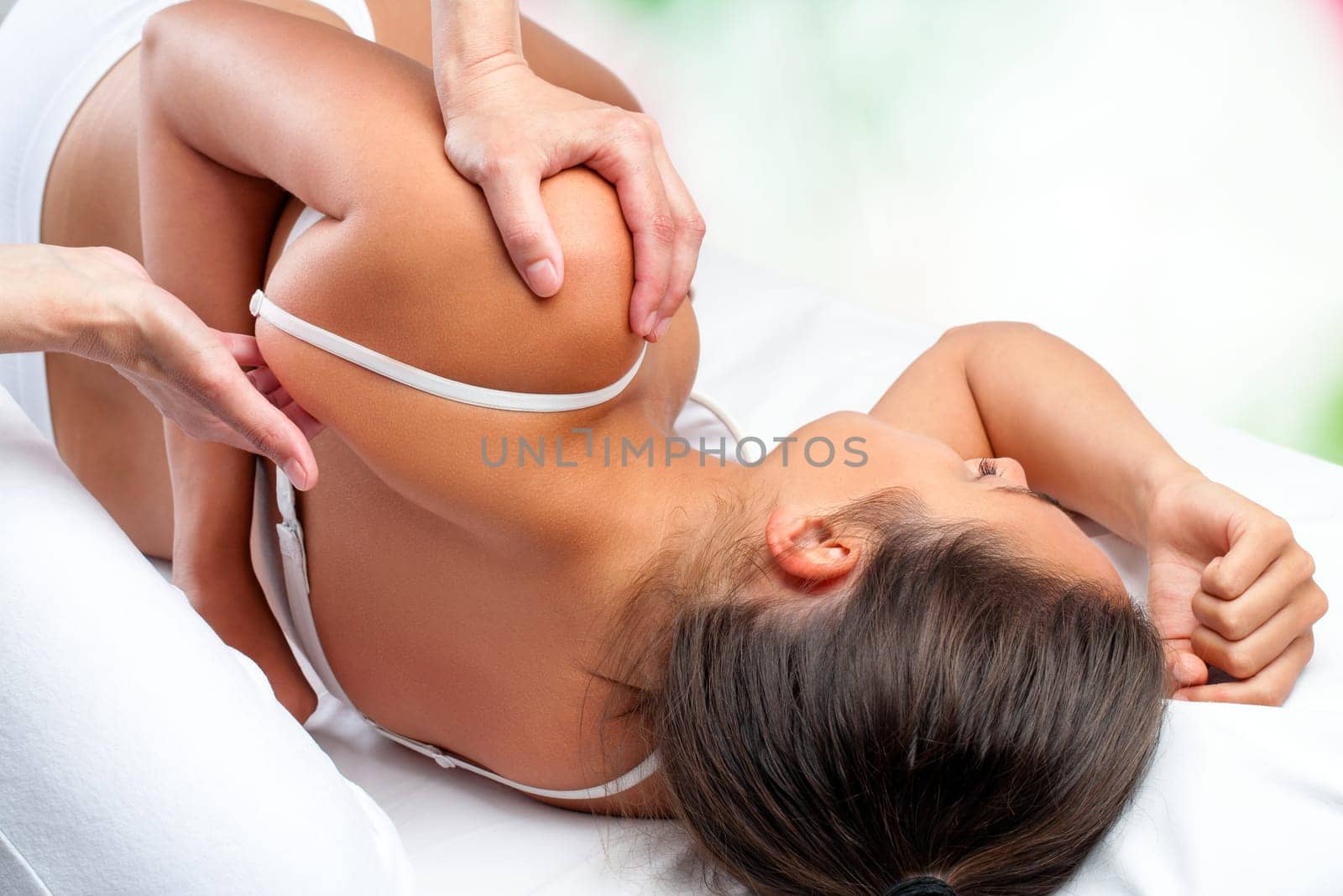 Close up top view of osteopath doing healing treatment on female shoulder blade.