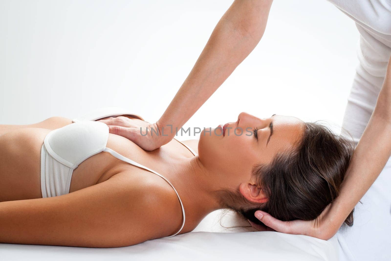 Close up of osteopath doing thorax manipulation massage on young woman.One hand doing physical force on chest and on hand behind head.
