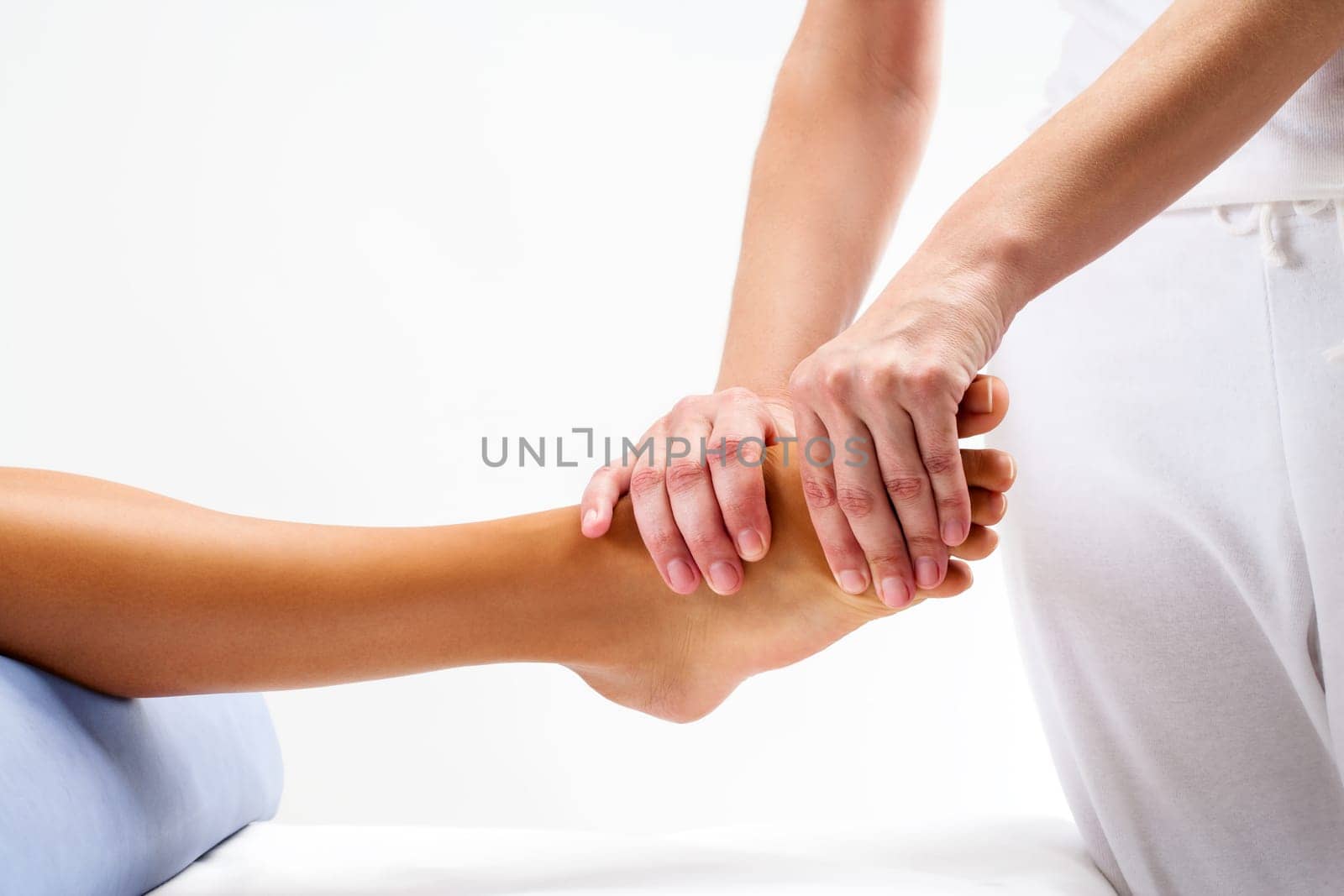 Osteopath doing reflexology massage on female foot.Isolated on light background.
