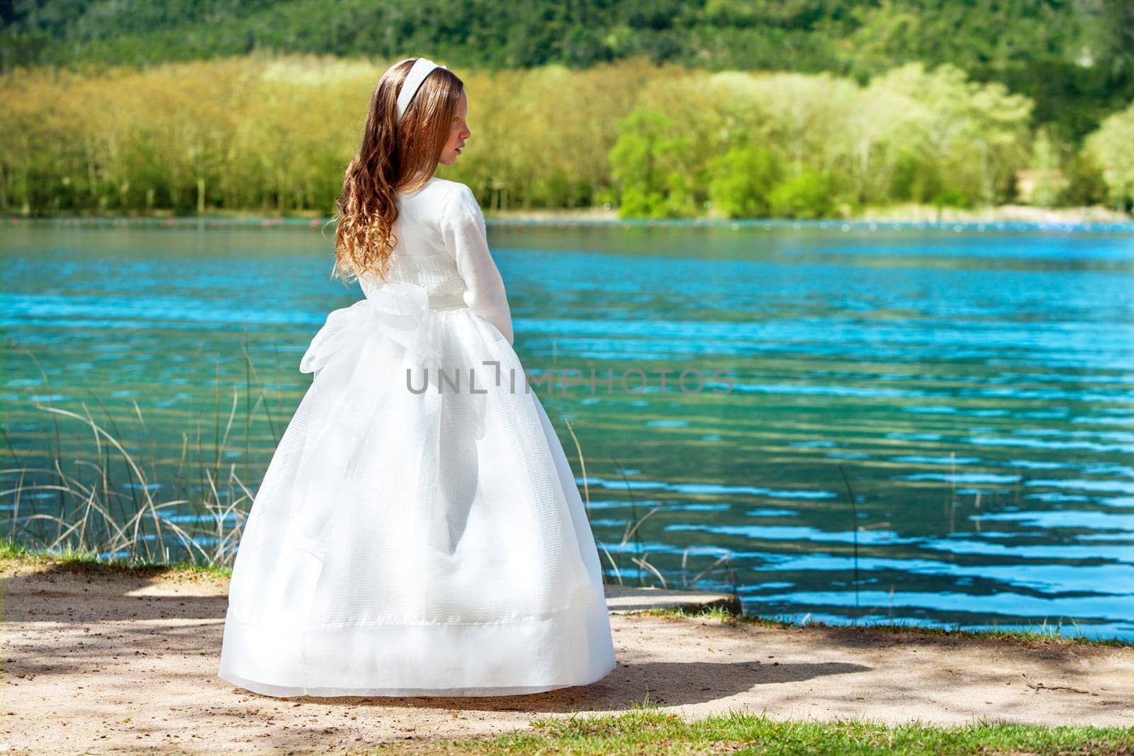 Full length portrait of cute girl in white dress at lake.