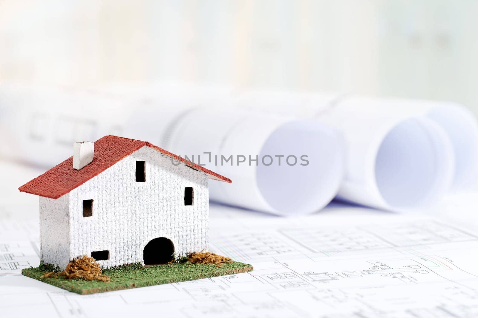 Close up of small toy house on architectural blueprints.