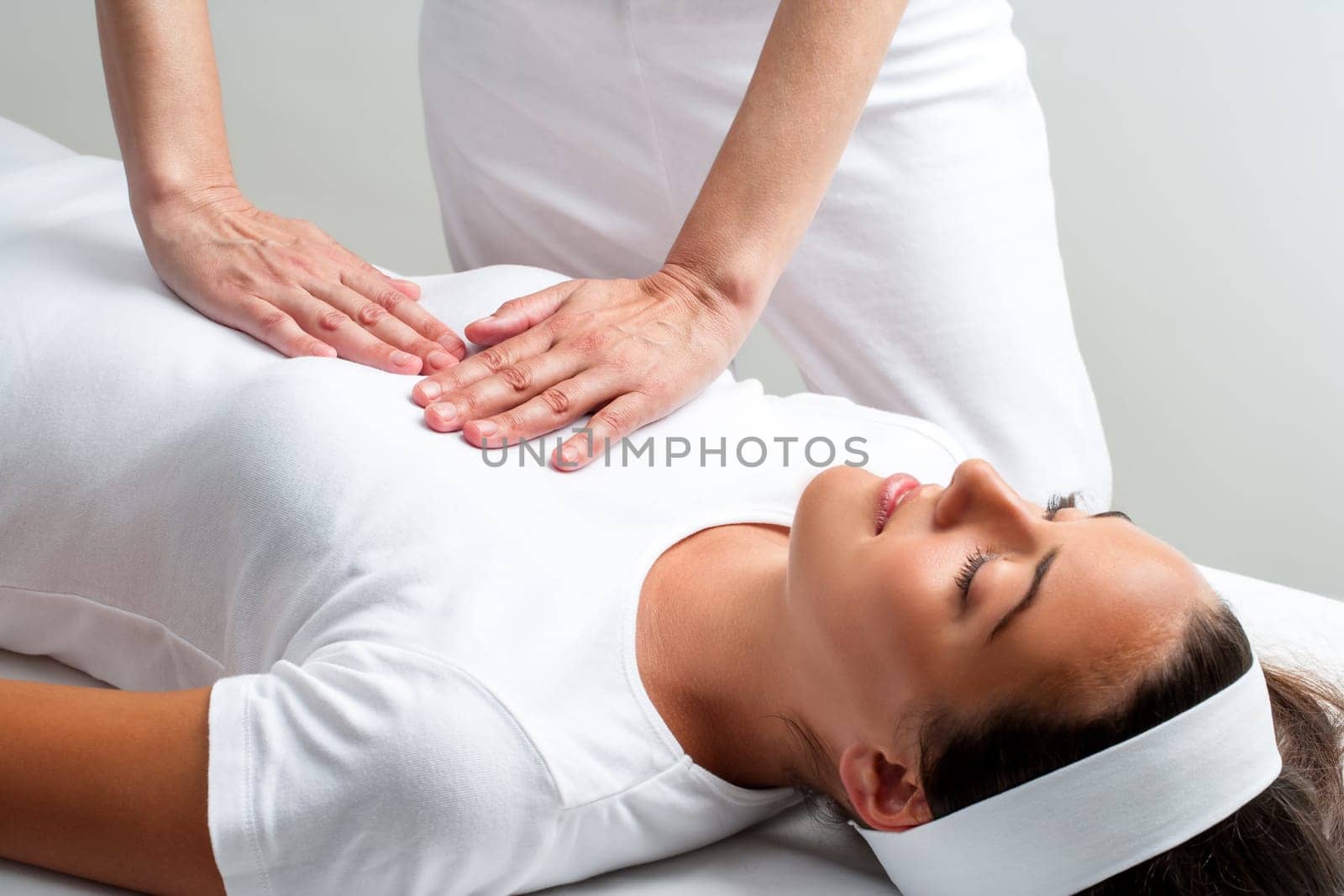 Close up of chiropractor pressing with hands on womans chest at reiki session.