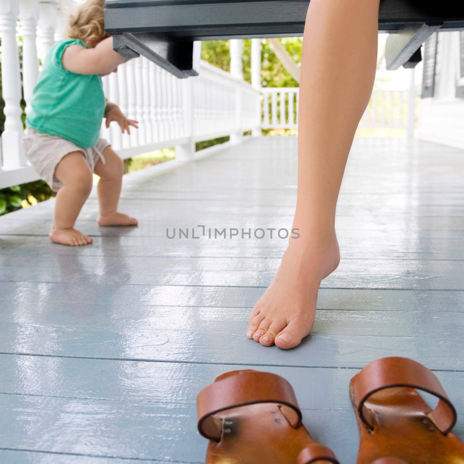 WomanŽs leg with a baby playing in a porch
