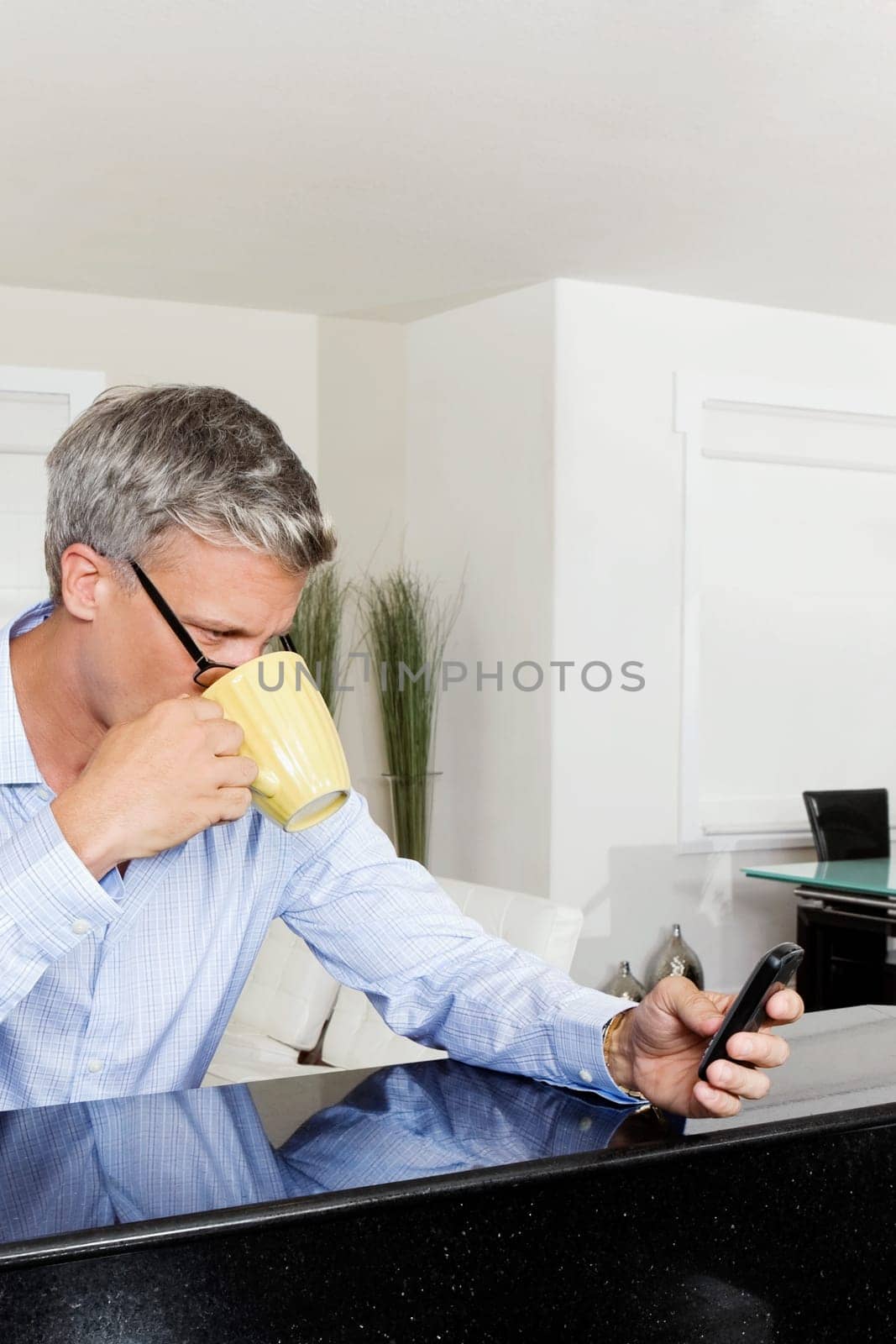 Man drinking coffee and text messaging on a mobile phone