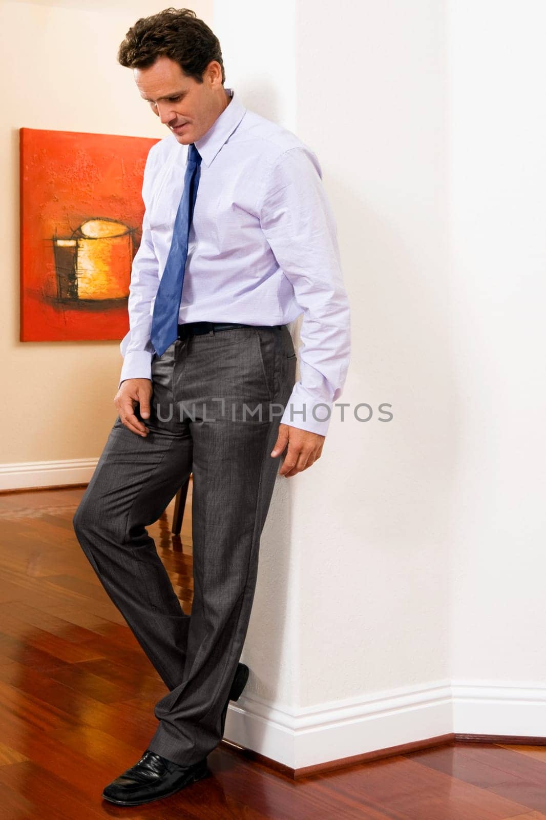 Businessman leaning against a wall in a house