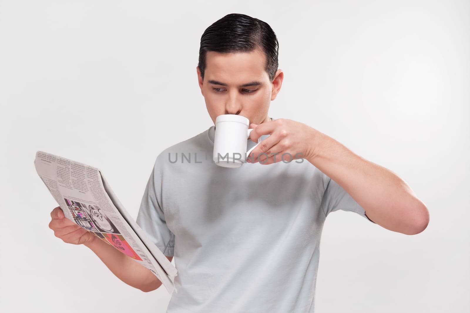 Close_up of a man reading a newspaper and drinking coffee
