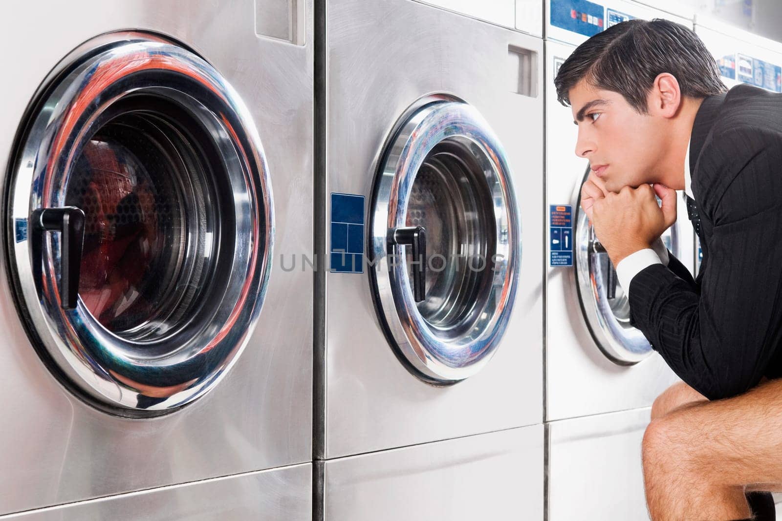 Businessman waiting in a laundromat