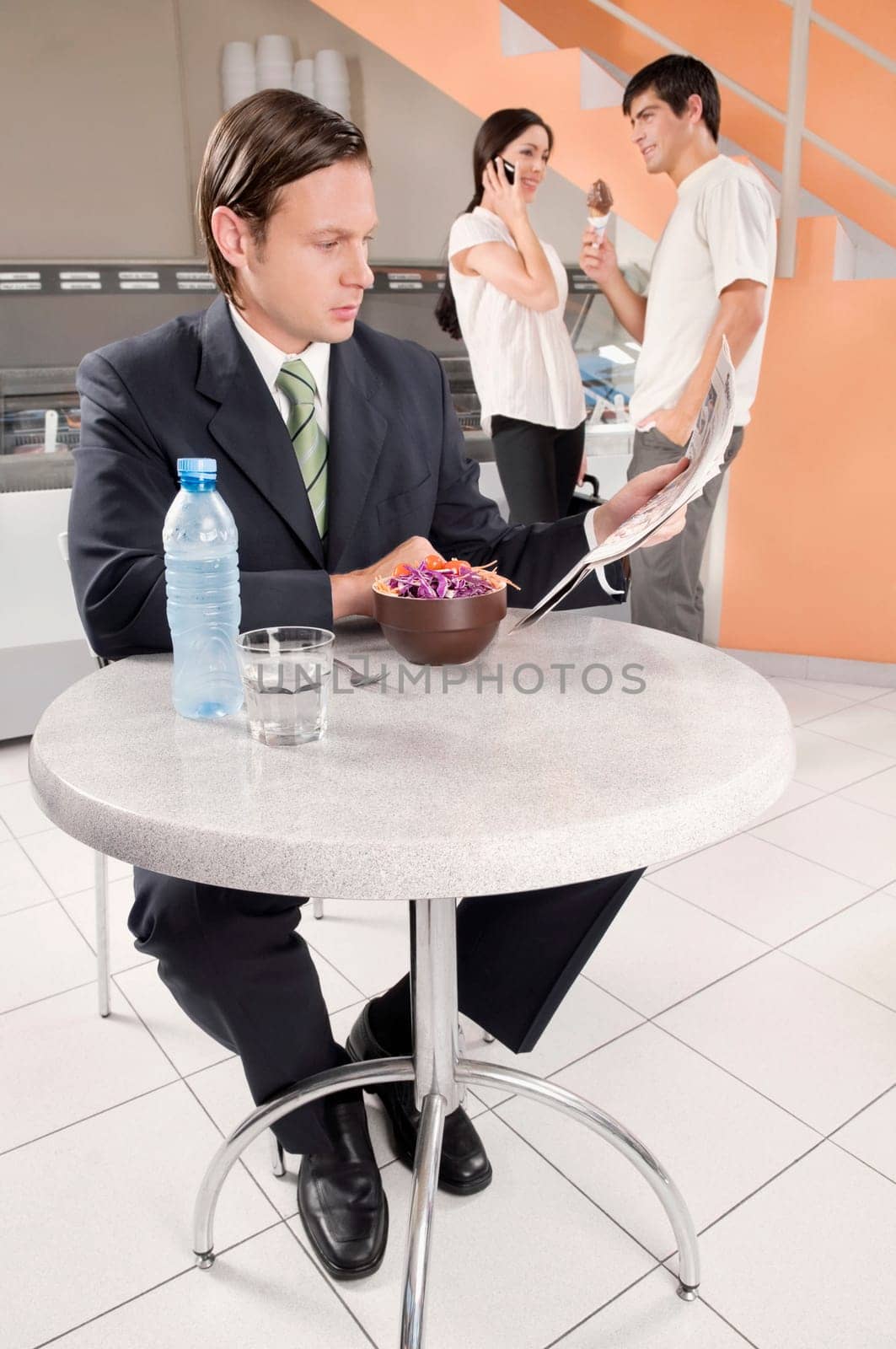 Businessman reading a newspaper in an ice cream parlor