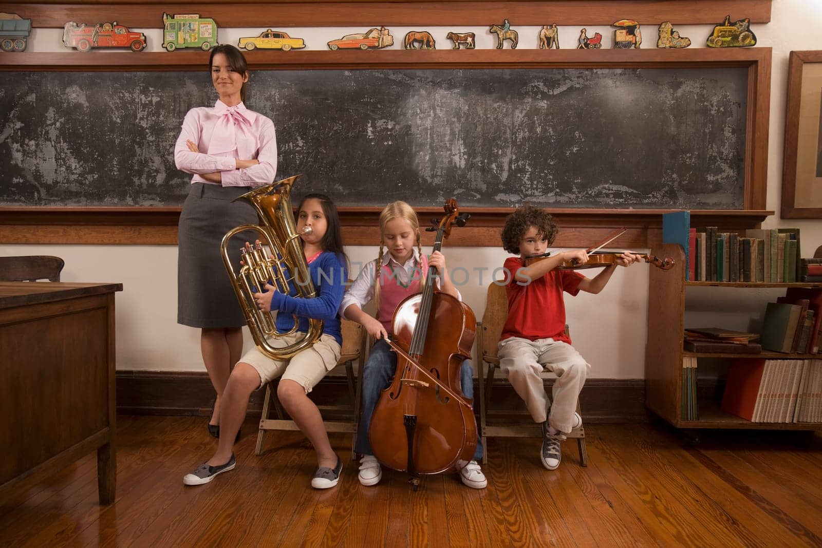 Students playing musical instruments with their teacher standing beside them