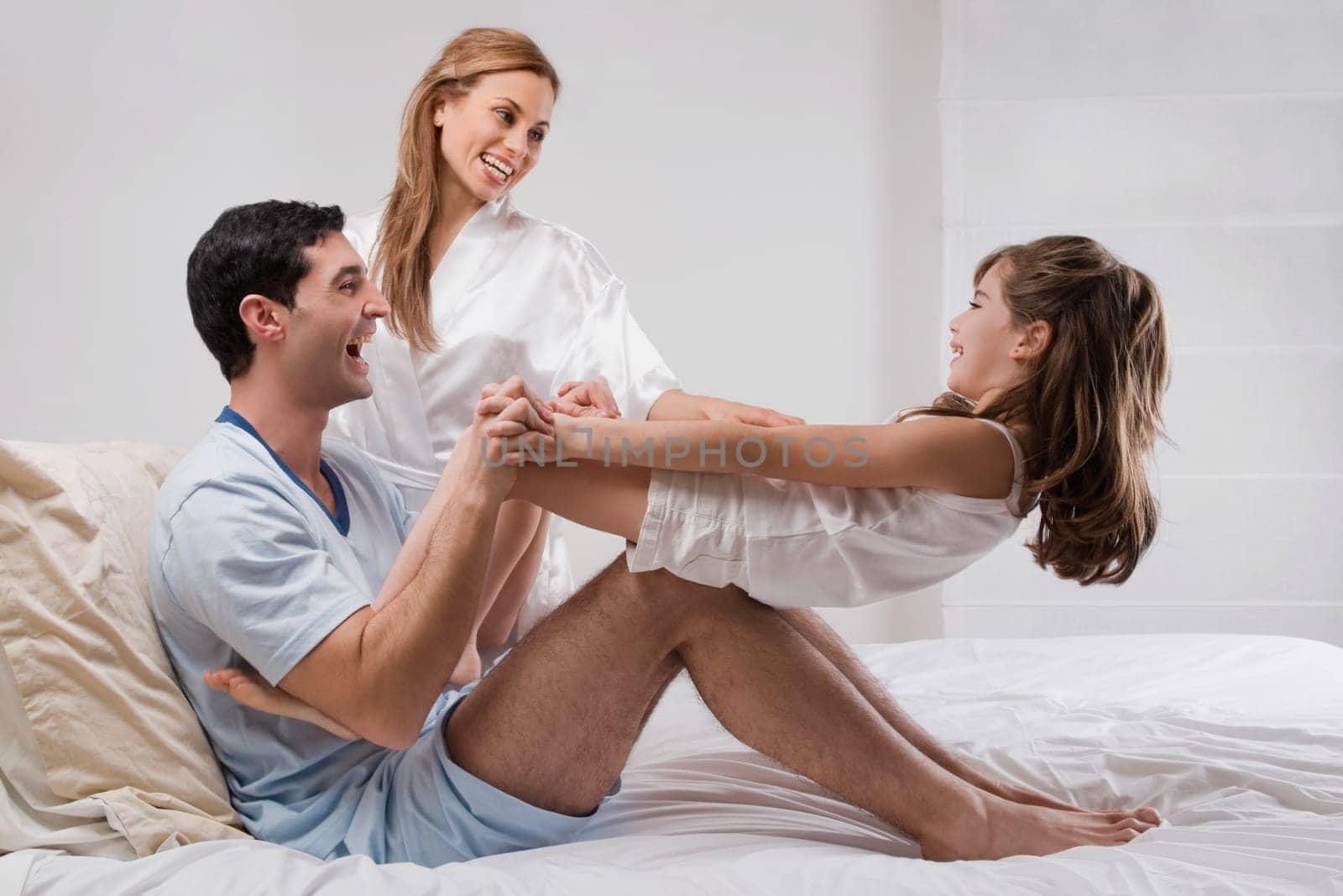 Mid adult couple playing on the bed with their daughter