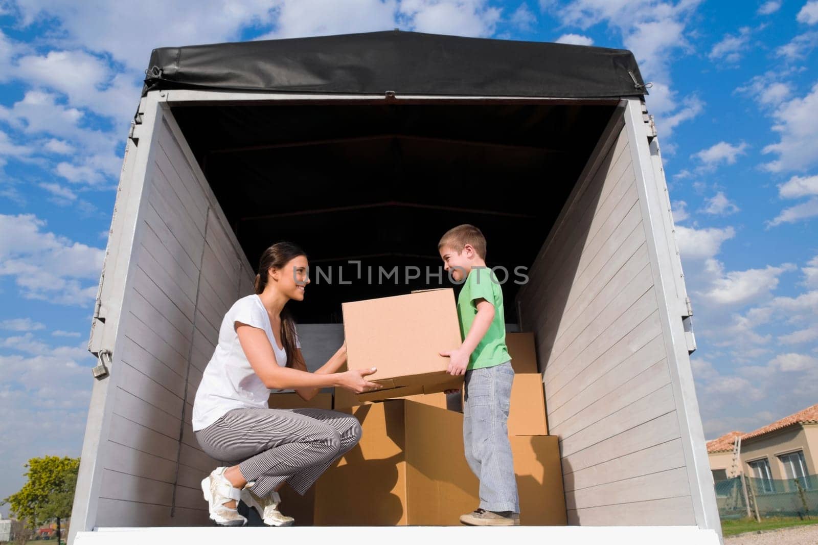 Low angle view of a young woman with her son carrying cardboard boxes