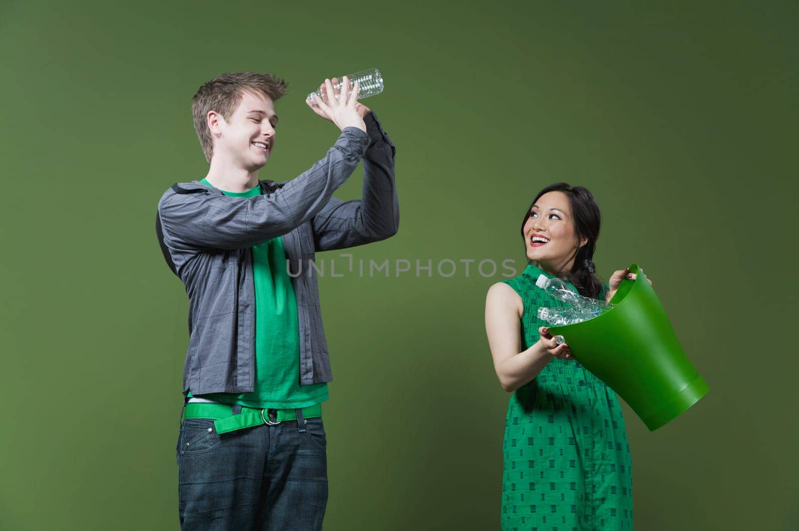 Woman holding a recycling bin and a man looking into an empty water bottle