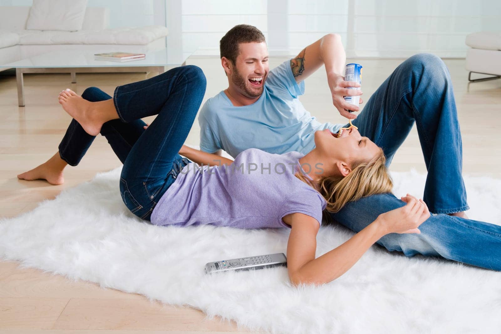 Young man feeding whipped cream from a bottle to a mid adult woman