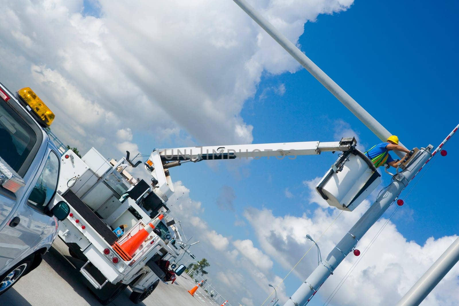 Low angle view of a maintenance engineer on a mobile crane repairing a security camera on a pole