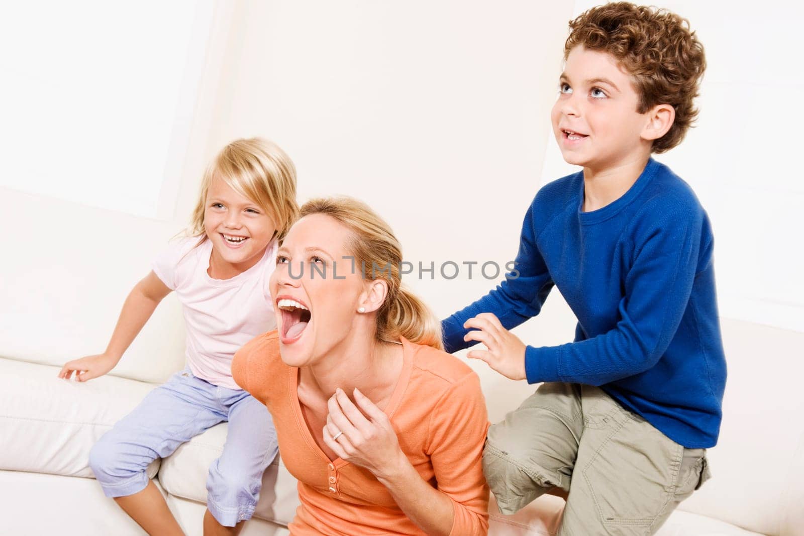 Woman playing with her son and a daughter in a living room
