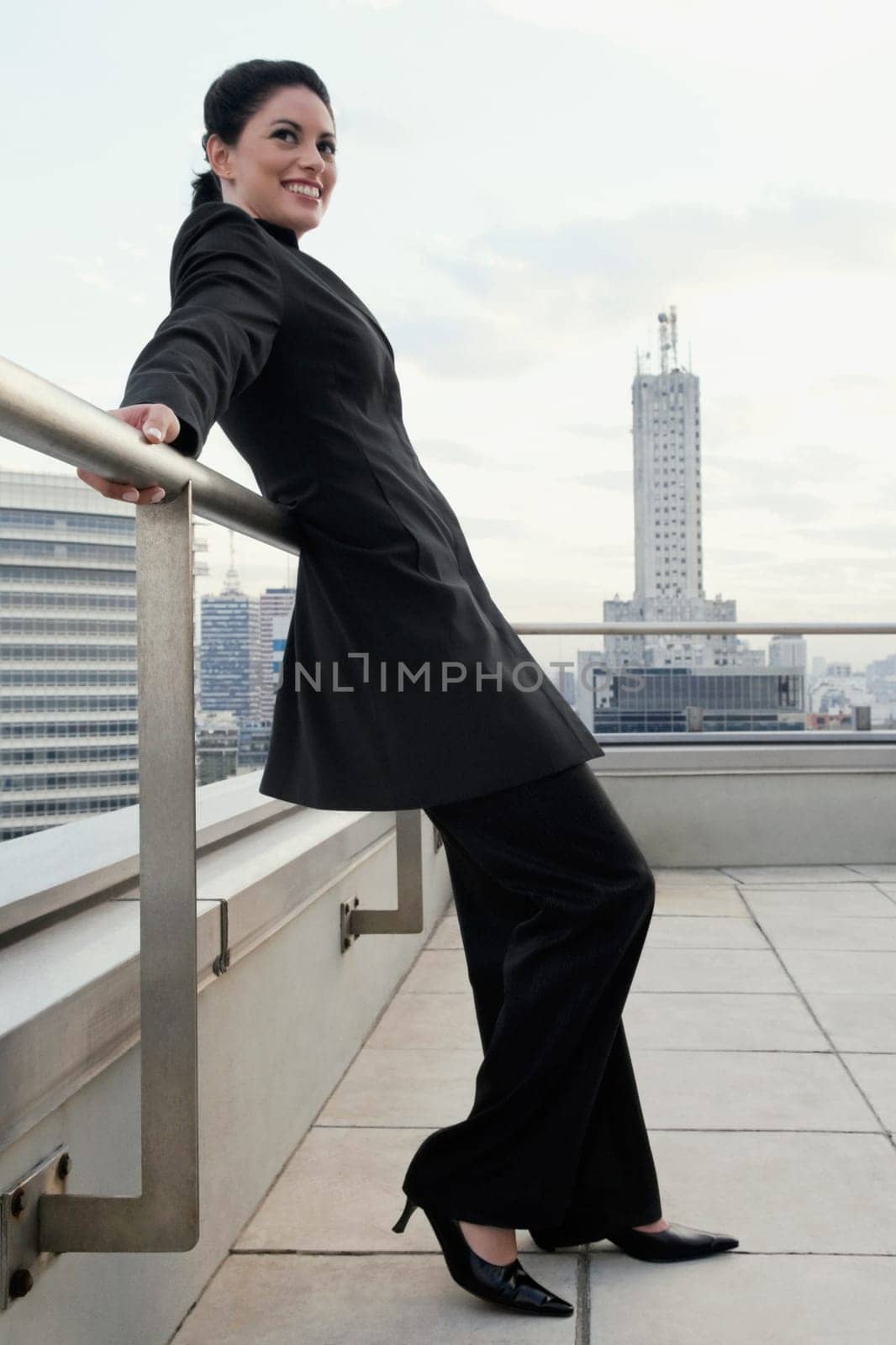 Side profile of a businesswoman leaning against a railing and smiling