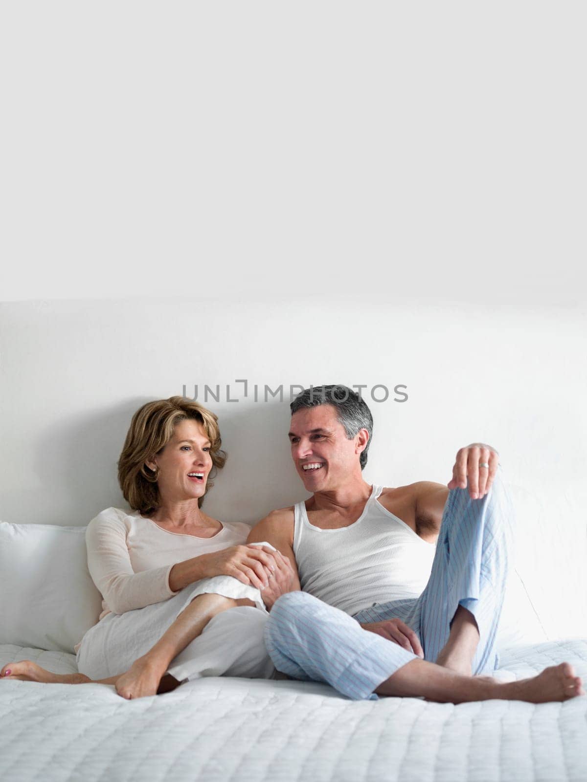 Couple reclining on the bed and talking to each other