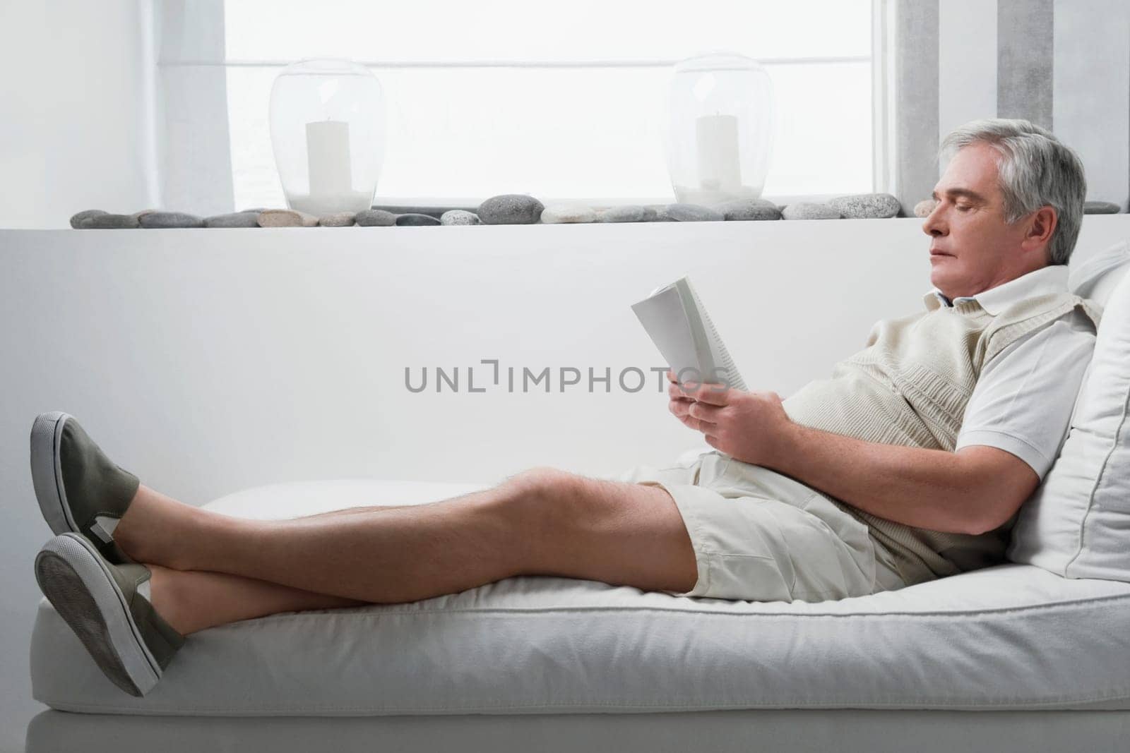 Senior man reclining on a chaise lounge and holding a book