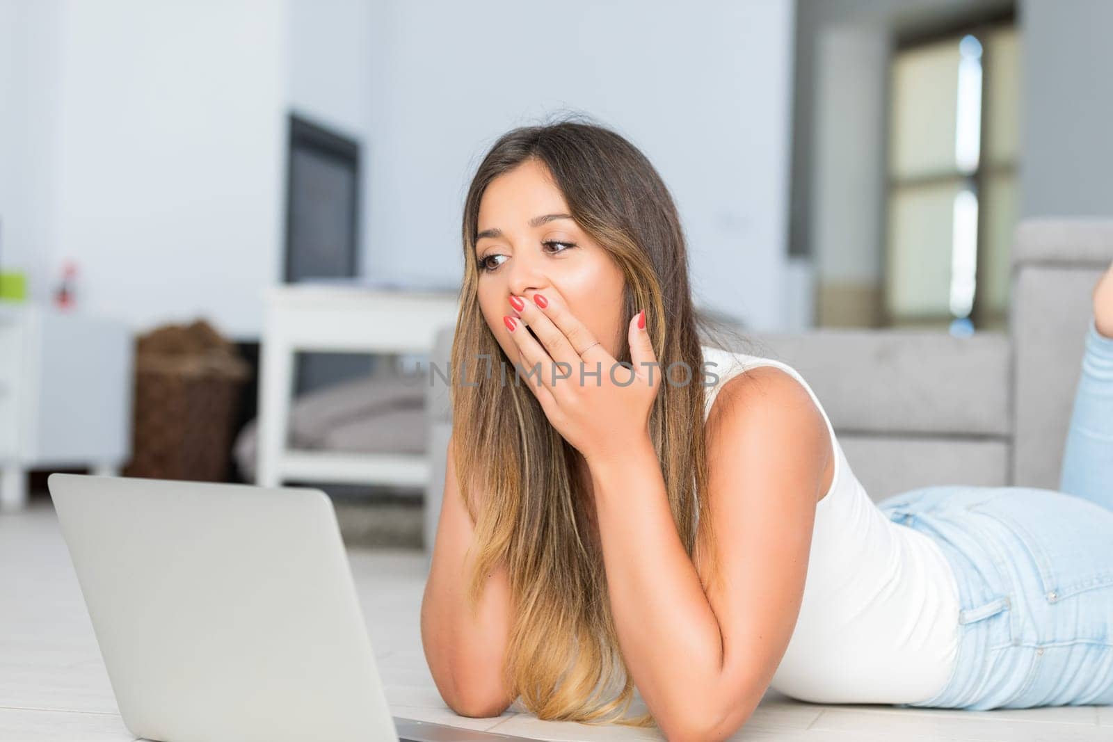 Beautiful young woman relaxing at home on her laptop computer