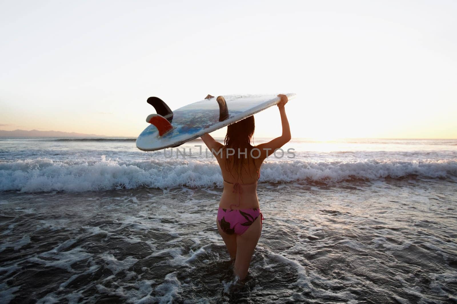 Woman carrying a surfboard on the beach