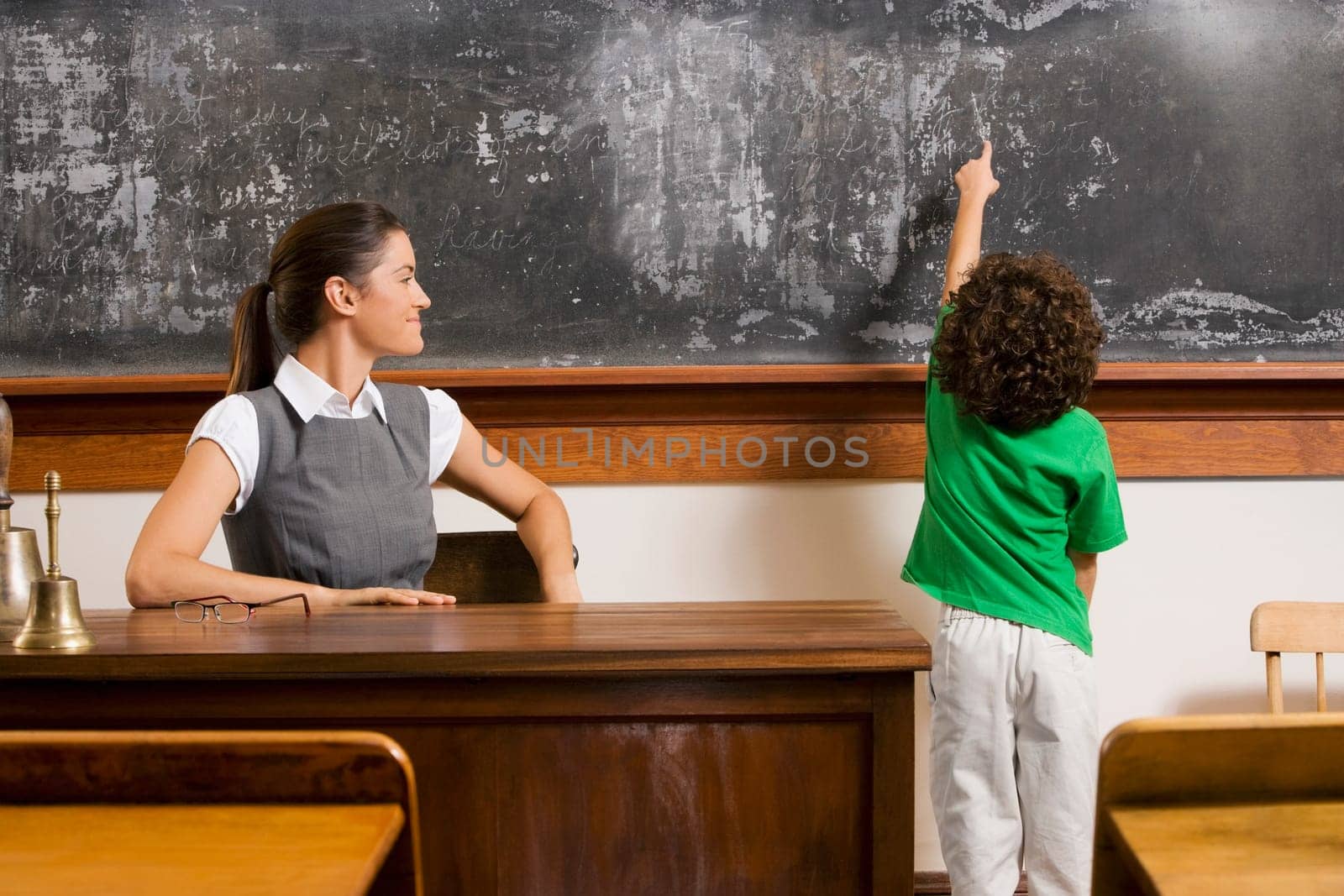 Schoolboy pointing at a blackboard with a teacher in a classroom
