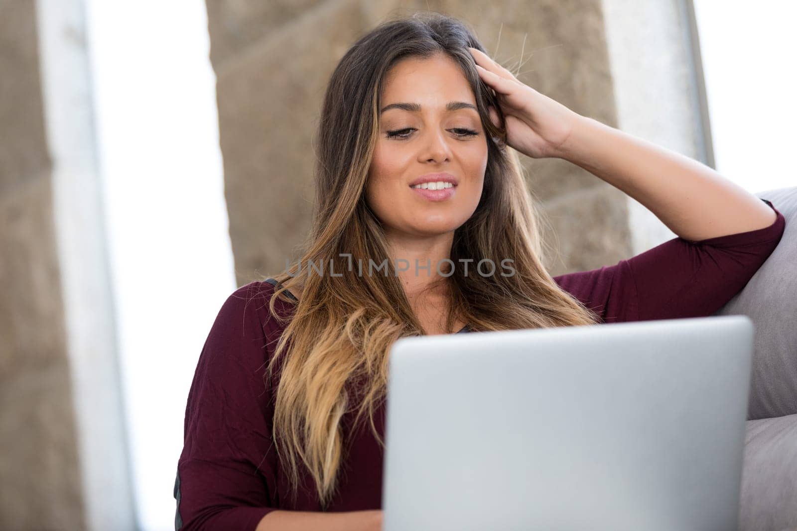 Beautiful young woman relaxing at home on her laptop computer