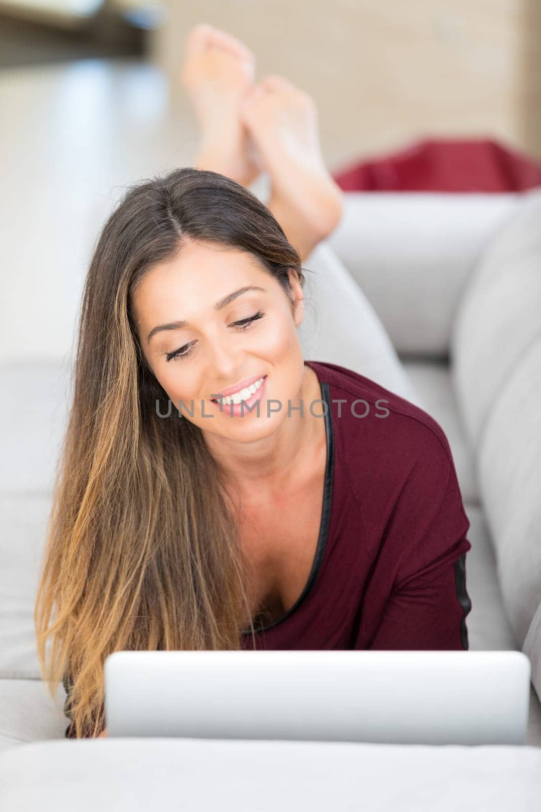 Beautiful young woman relaxing at home on her laptop computer