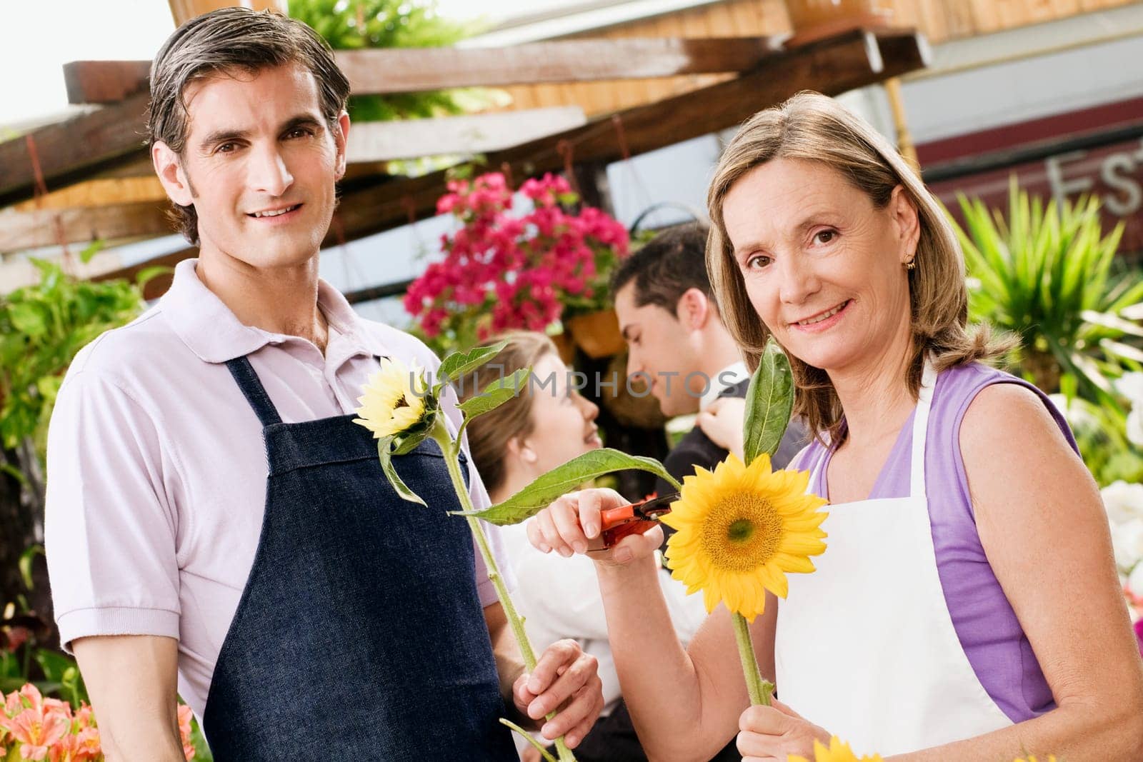 Woman pruning flowers with a man standing beside her