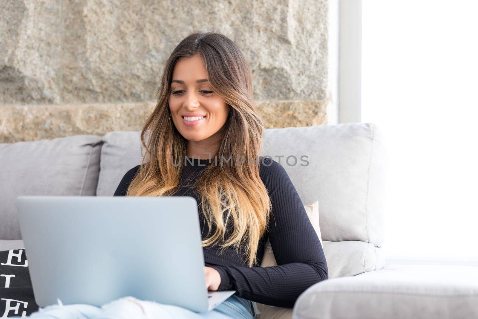 Beautiful young woman relaxing at home on her laptop computer