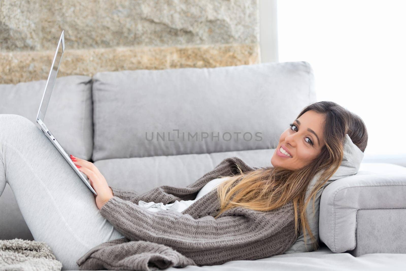 Beautiful young woman relaxing at home on her laptop computer