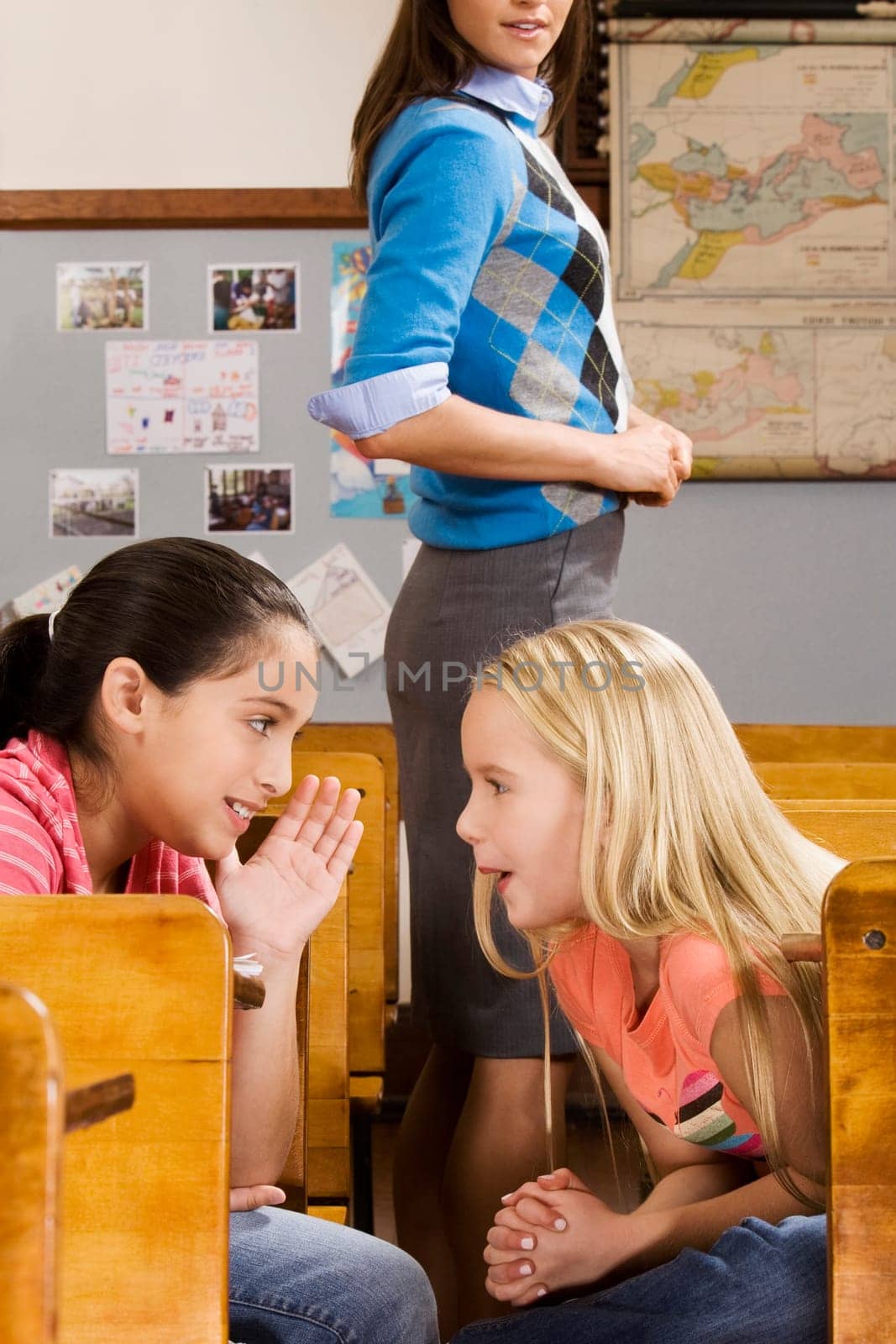 Schoolgirl whispering to her friend in a classroom