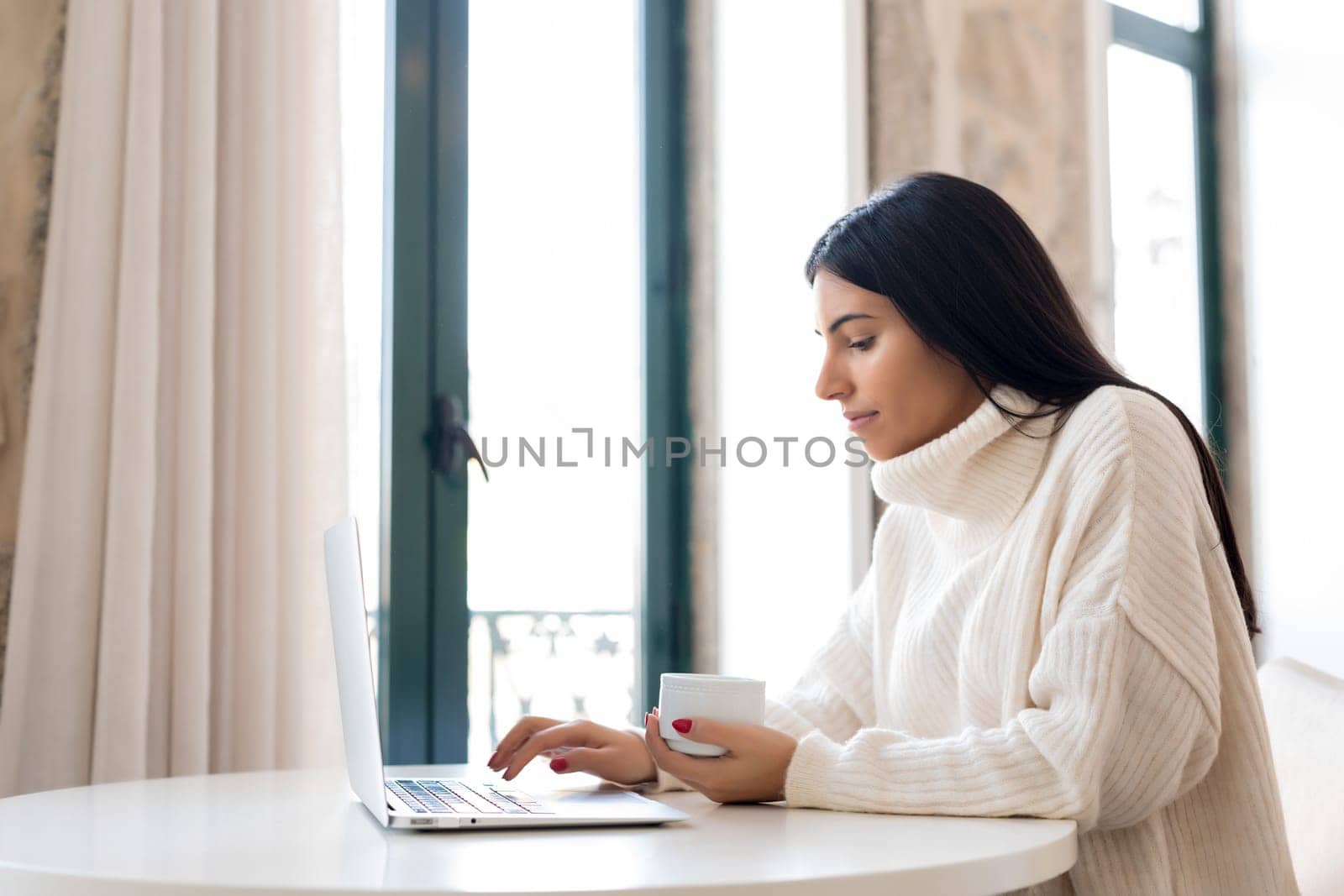 Beautiful young woman relaxing at home on her laptop computer