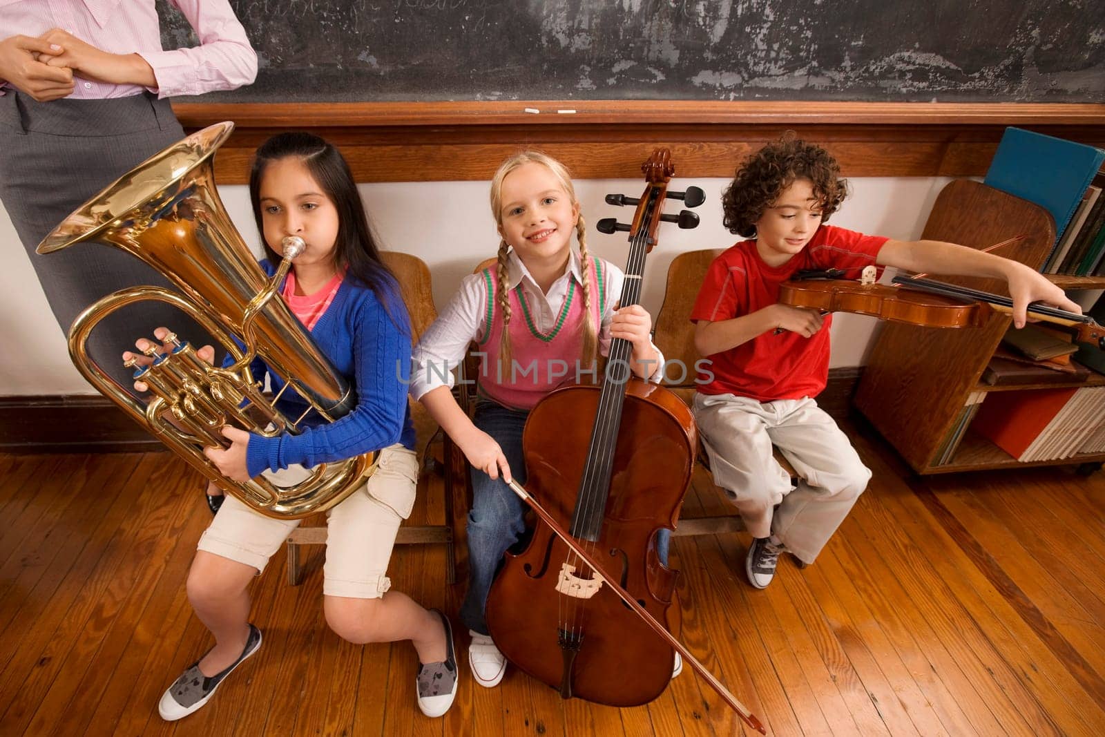 Three students playing musical instruments in a classroom