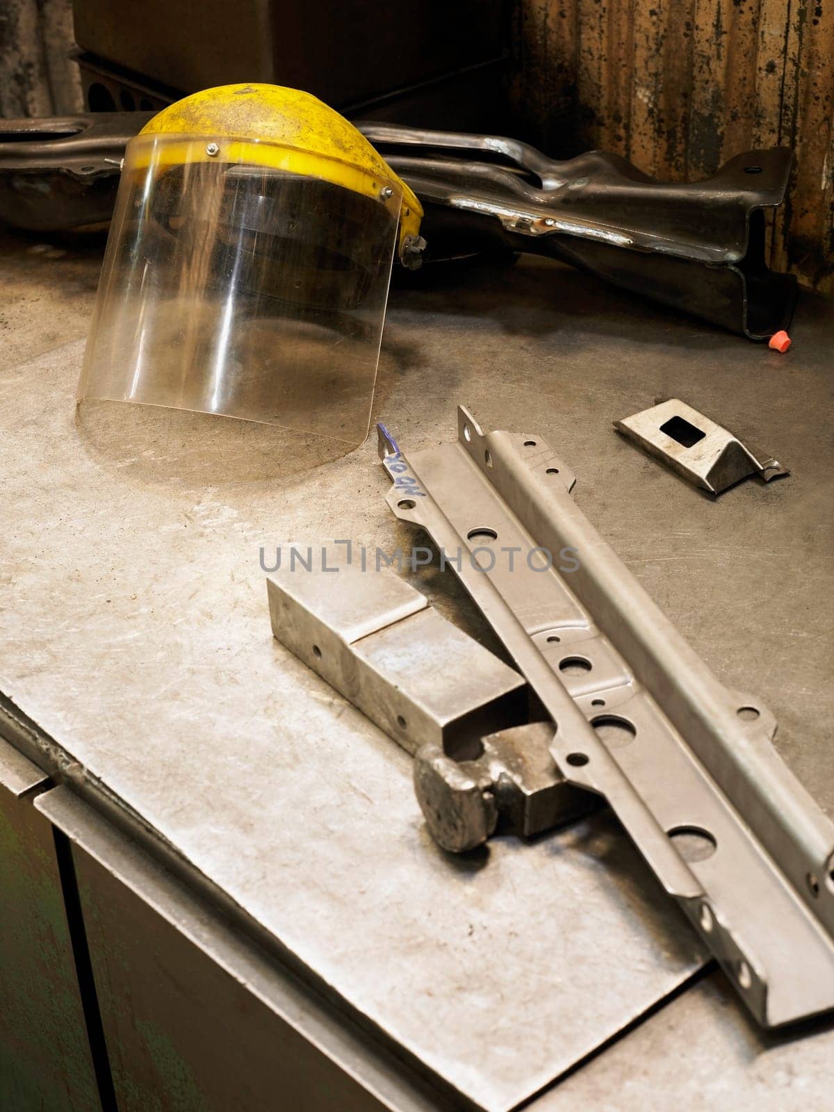 Close_up of a metal object and a helmet visor on a workbench
