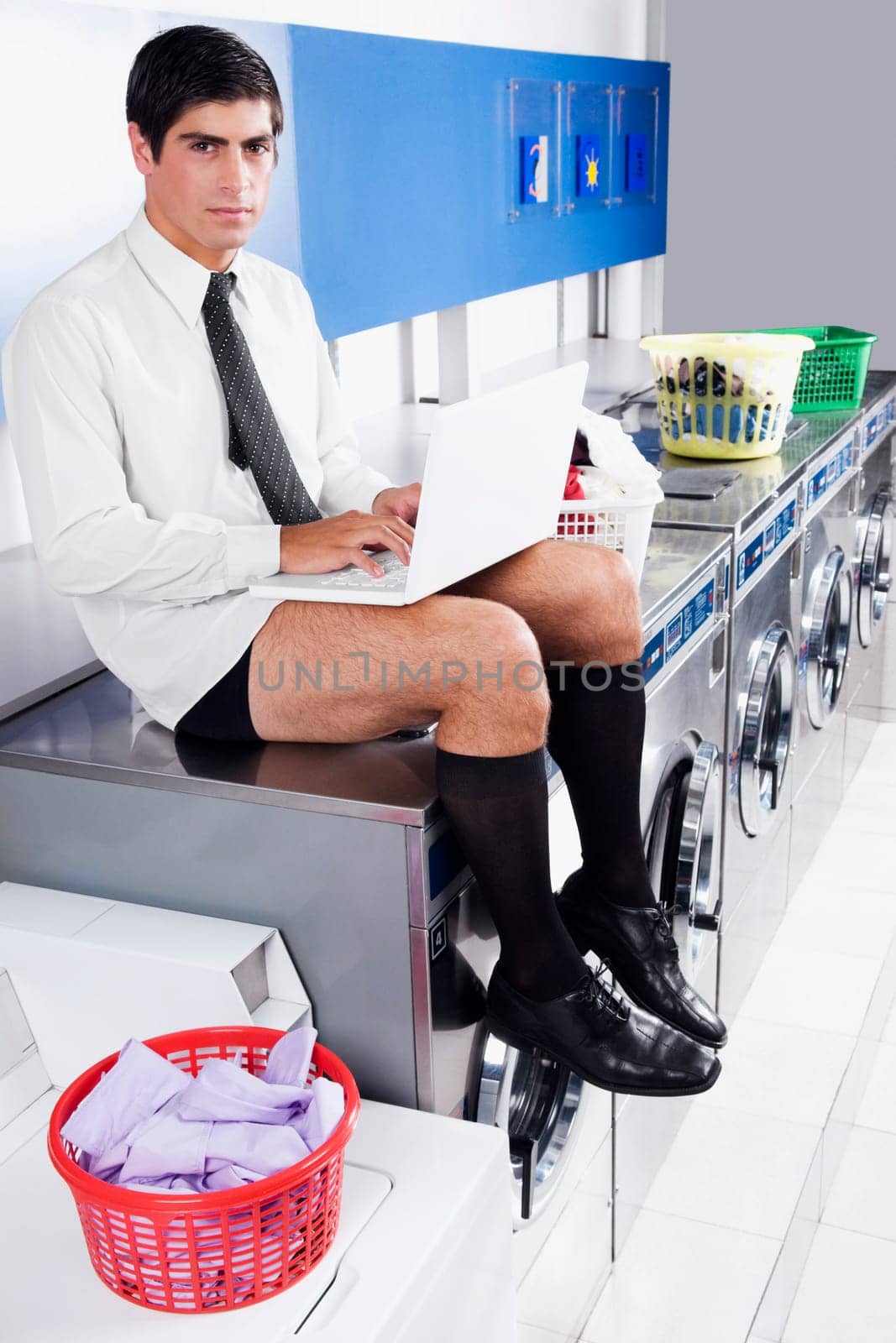 Businessman working on a laptop in a laundromat