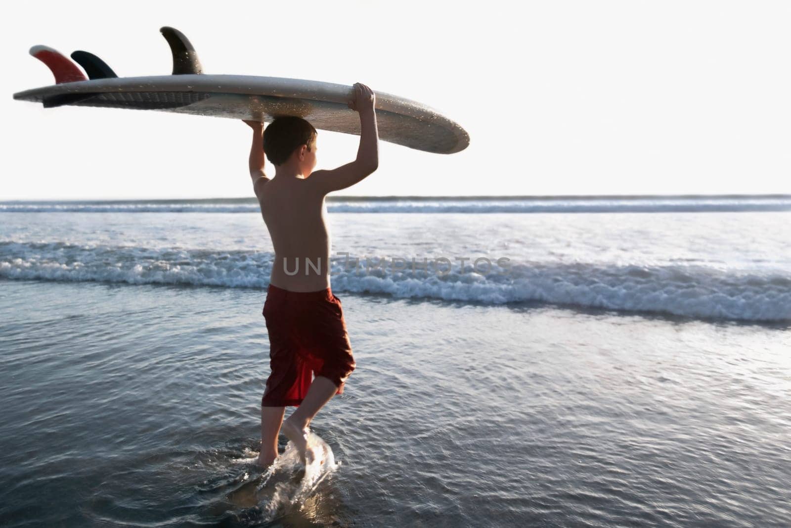 Boy carrying a surfboard on the beach