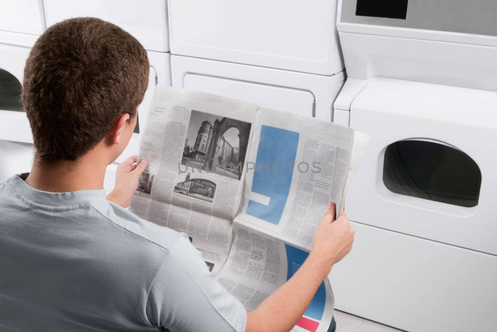 Man reading a newspaper in a laundromat