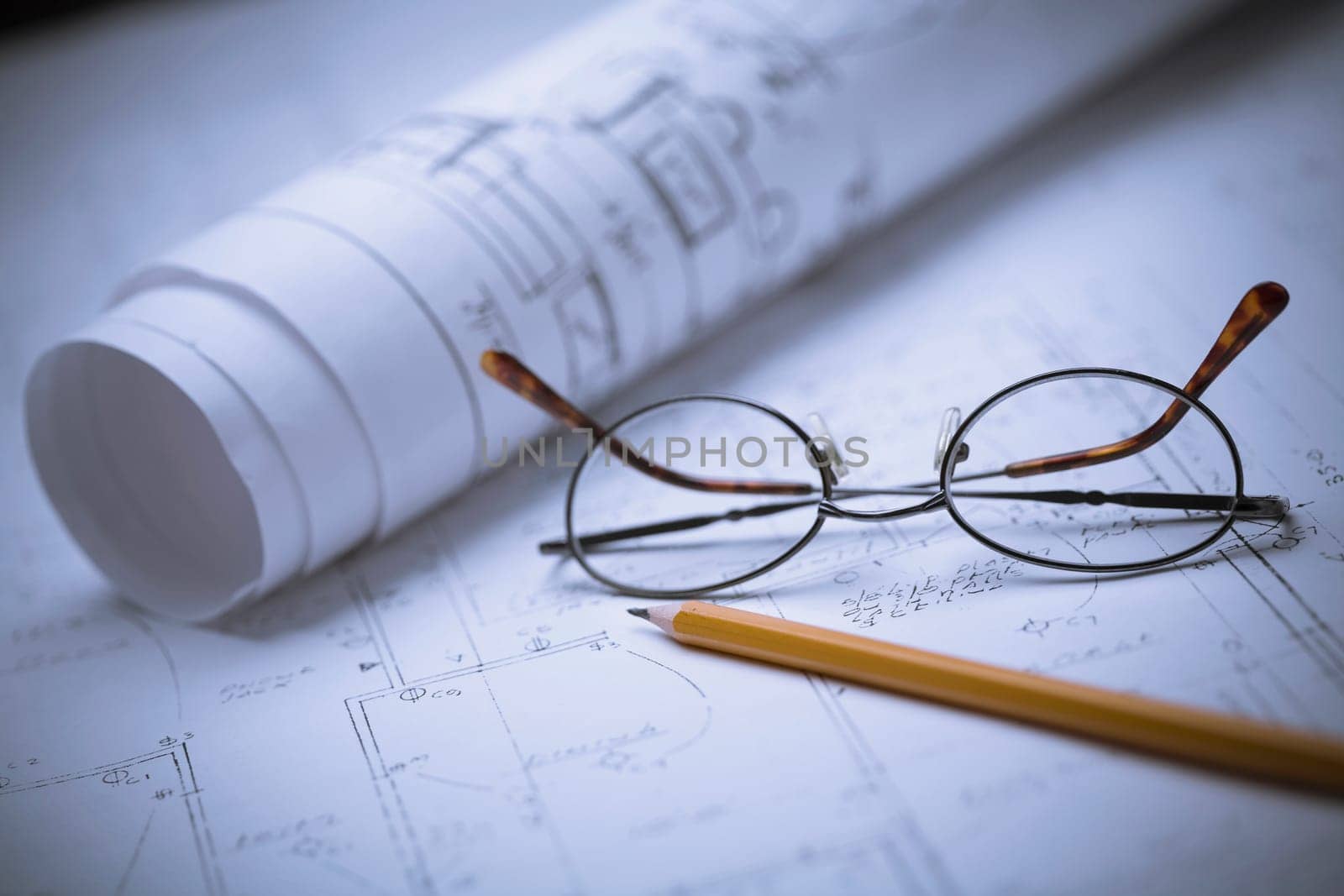 Close_up of eyeglasses and a pencil on a blueprint