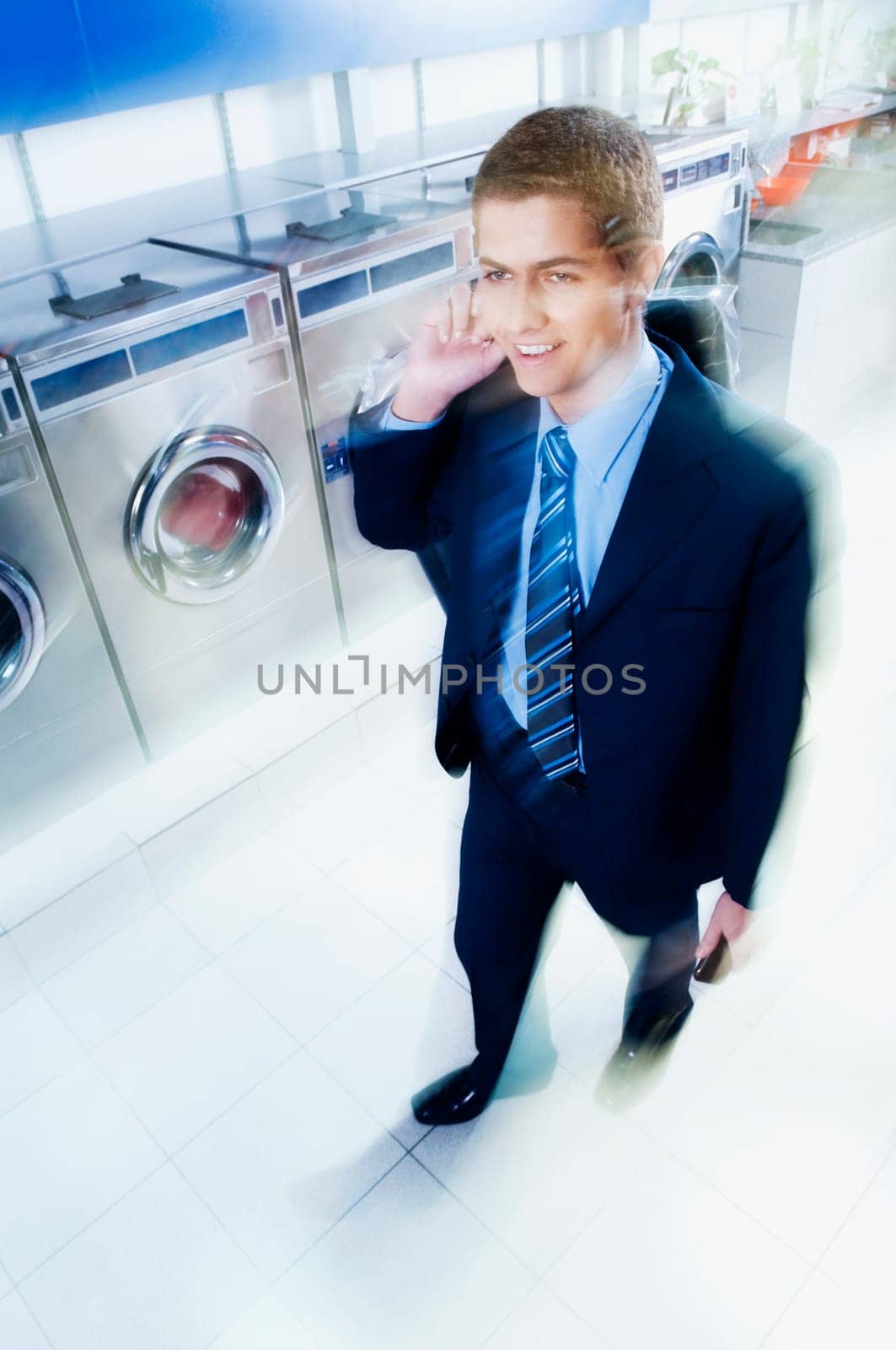 Businessman talking on a mobile phone in a laundromat