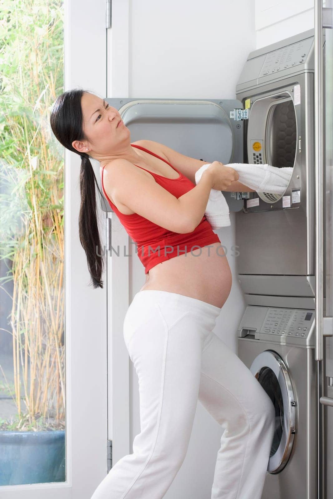 Pregnant woman pulling clothes out from a washing machine