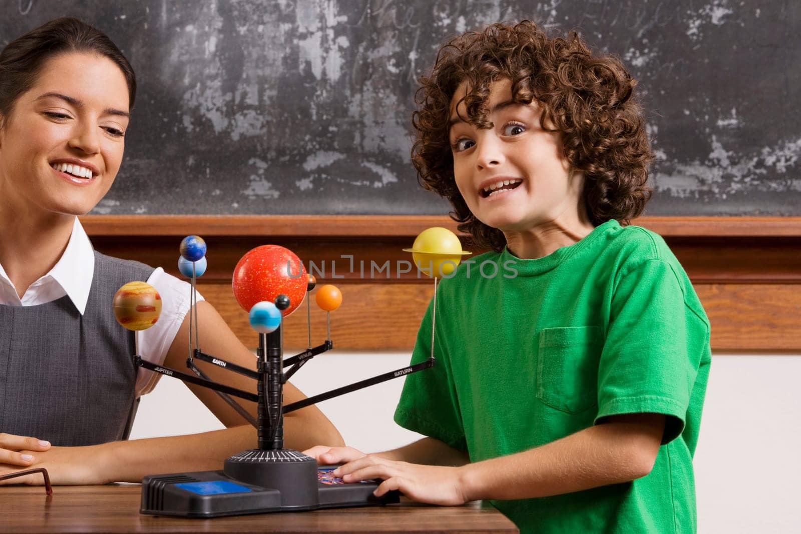 Schoolboy and his teacher with model of solar system in a classroom