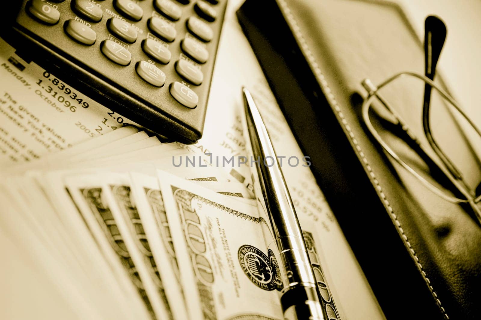 Close_up of a pen with a calculator and eyeglasses on a financial newspaper