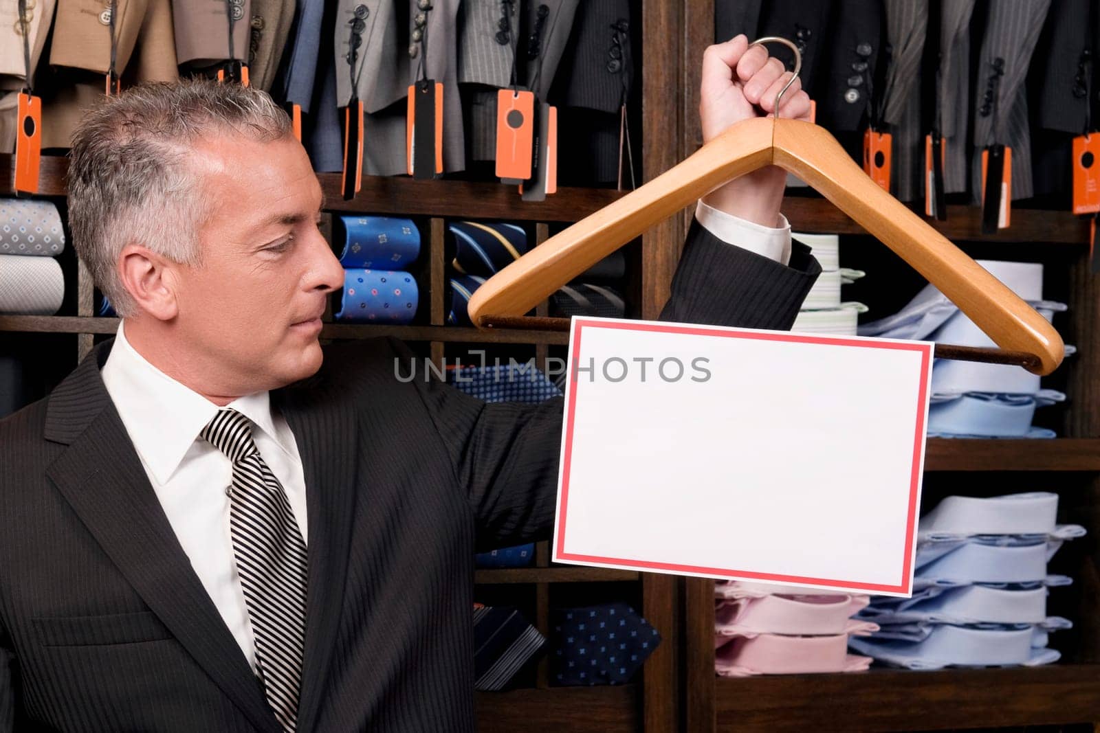 Businessman holding a hanger with blank signboard in a clothing store