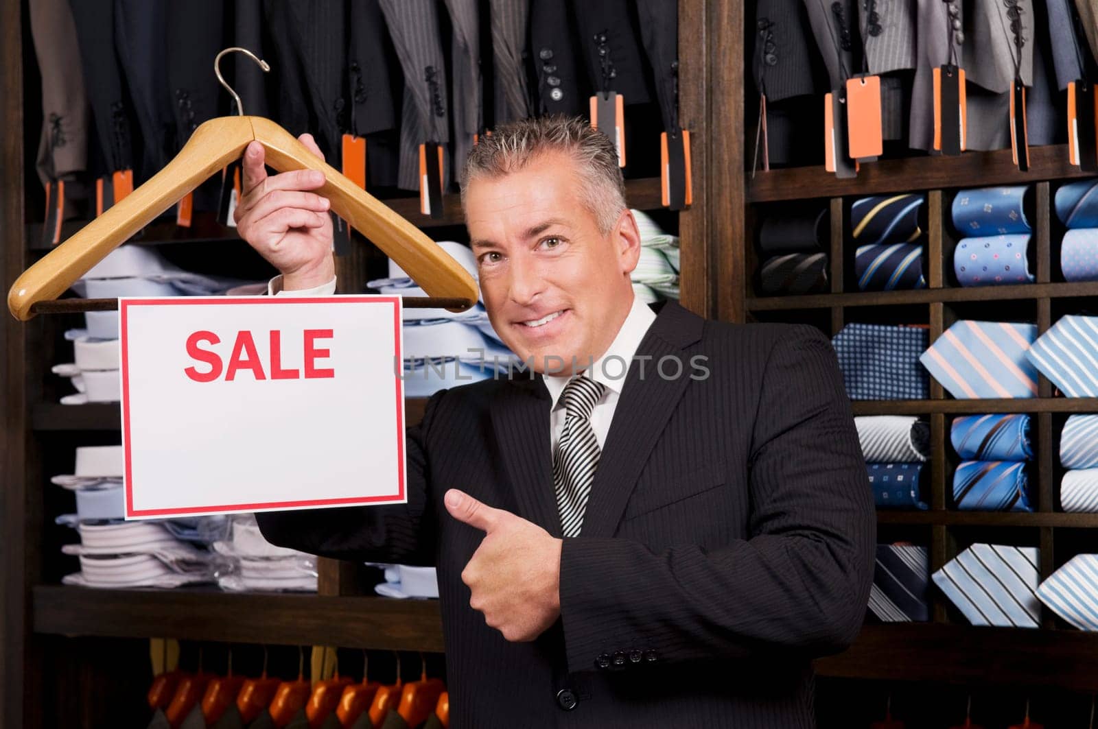 Businessman holding a Sale sign in a clothing store
