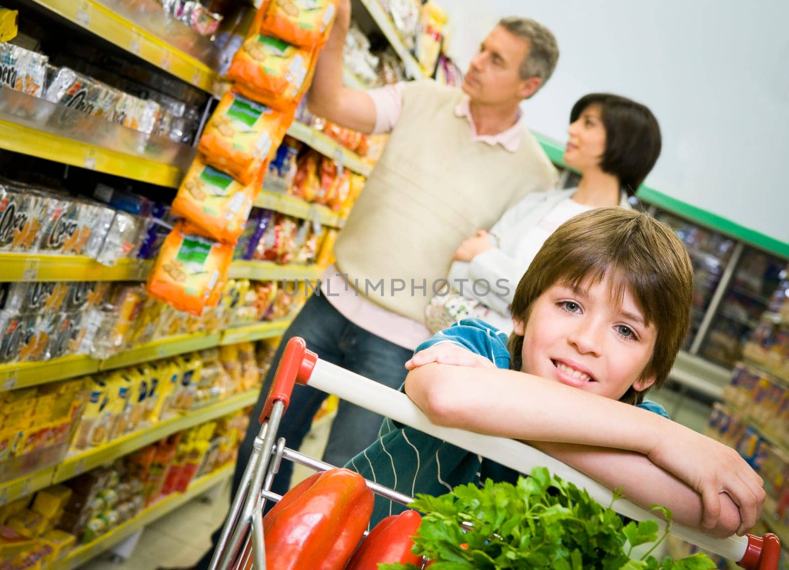 Portrait of a boy in a supermarket with his parents shopping behind him