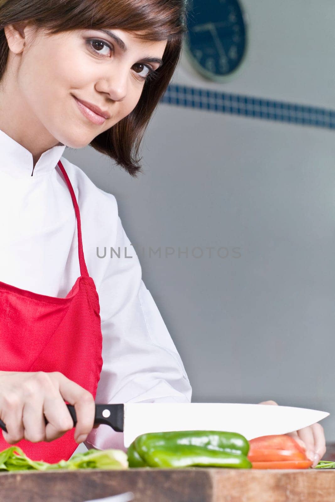 Female chef chopping bell pepper with a knife