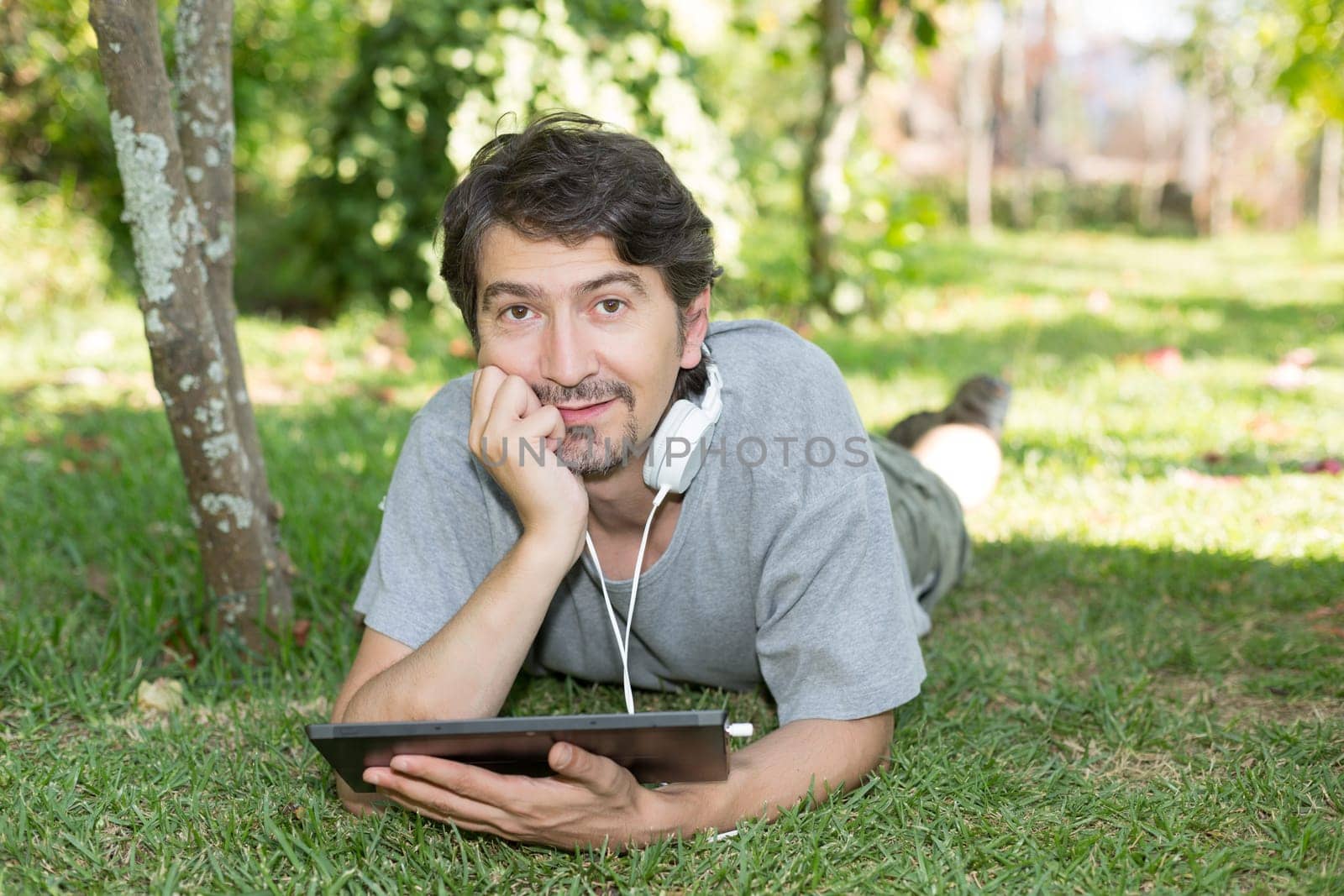 Young man relaxing with a tablet computer at a garden